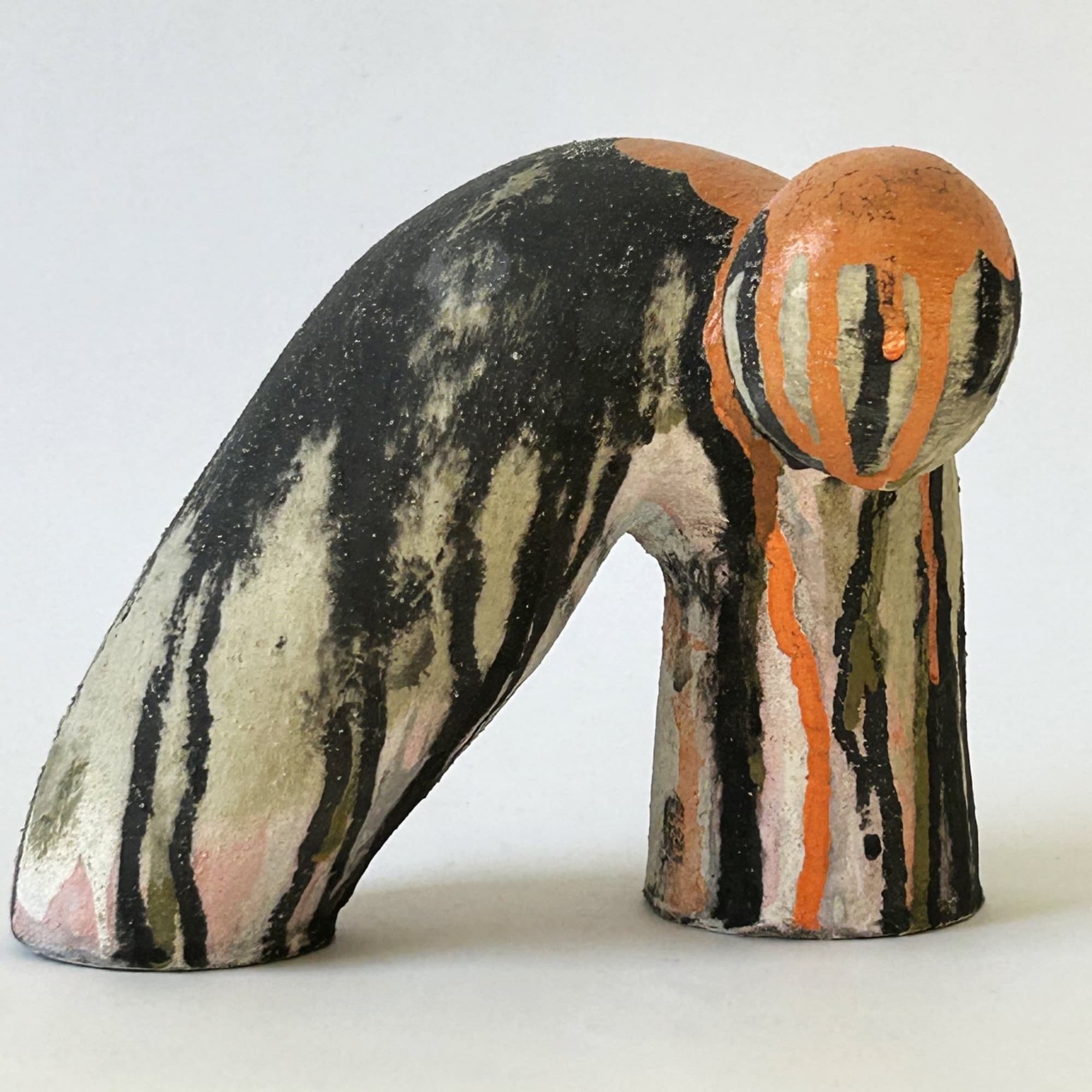 Arching ceramic sculpture striped in black, cream and olive, with a bulb at the crest banded in orange and white.