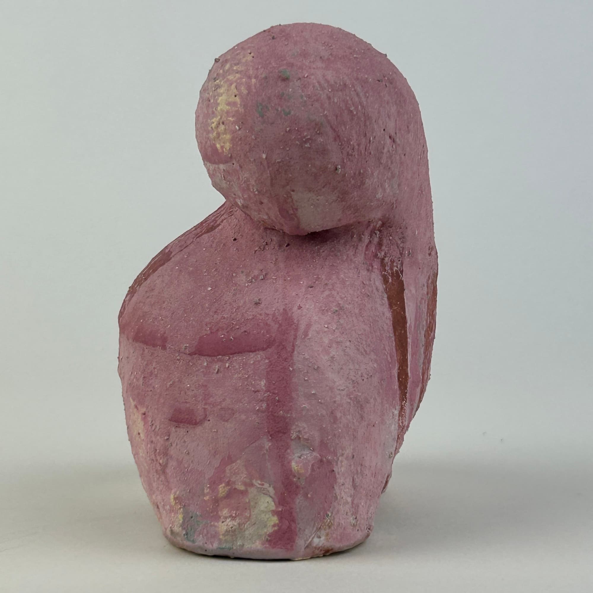 Compact upright ceramic sculpture in dusty rose, a rounded head folded down against a heavy shoulder.