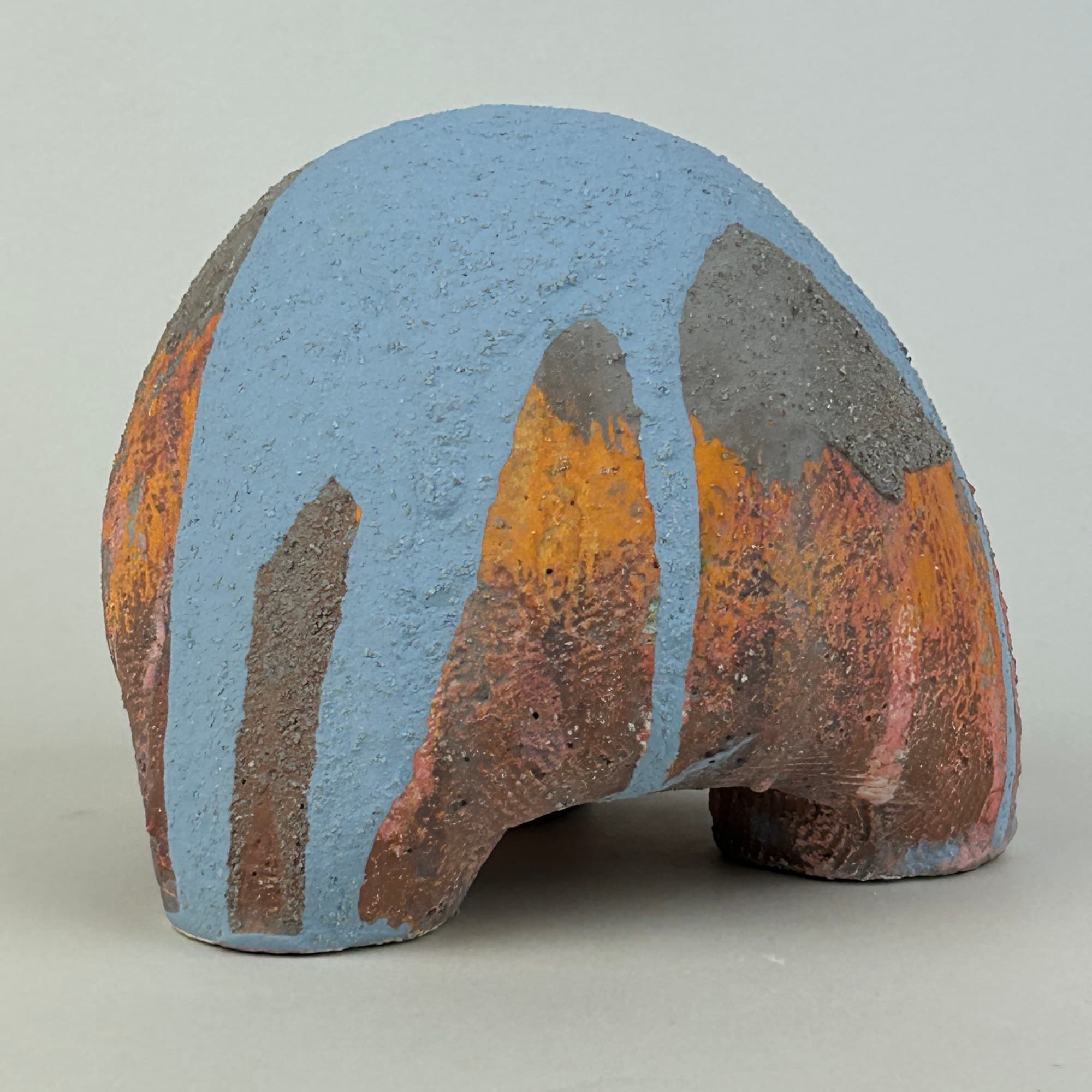 Dome-shaped ceramic sculpture in powder blue with orange, grey and ochre glaze running in broad vertical bands.