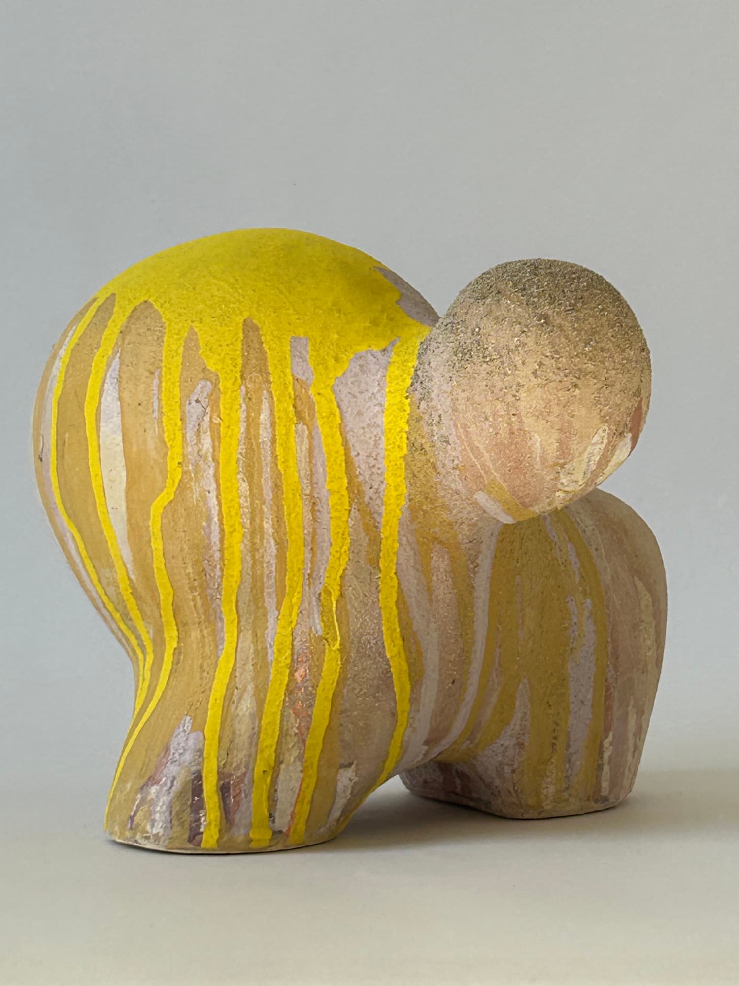 Ceramic sculpture in blush and ochre with bright yellow glaze poured over the crown and streaking down the body.