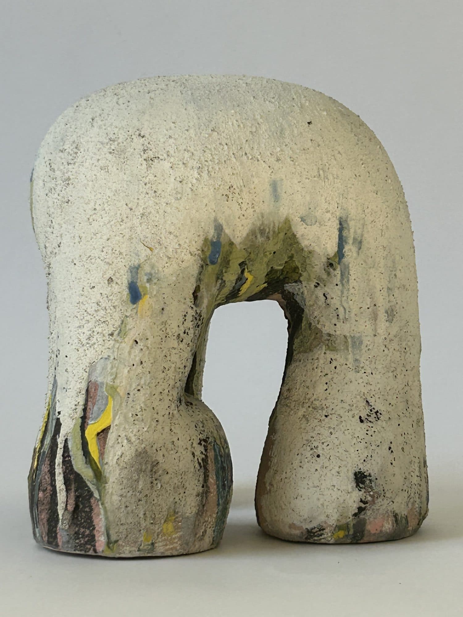 Chalk-white ceramic arch, its legs streaked with black and blue where the glaze has run down into the base.