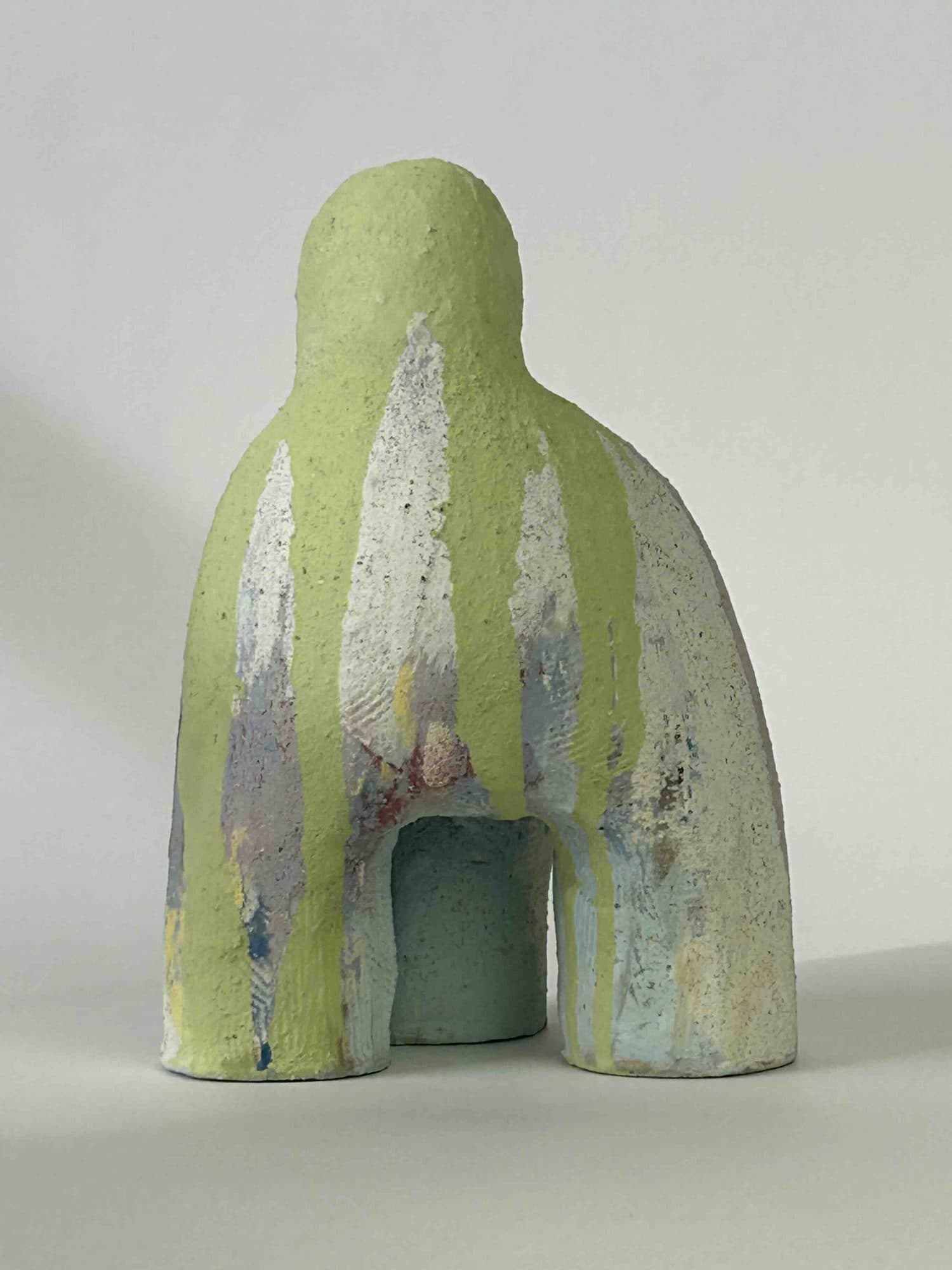 Standing ceramic sculpture striped in chartreuse and pale green, an arch opening beneath the heavy body.