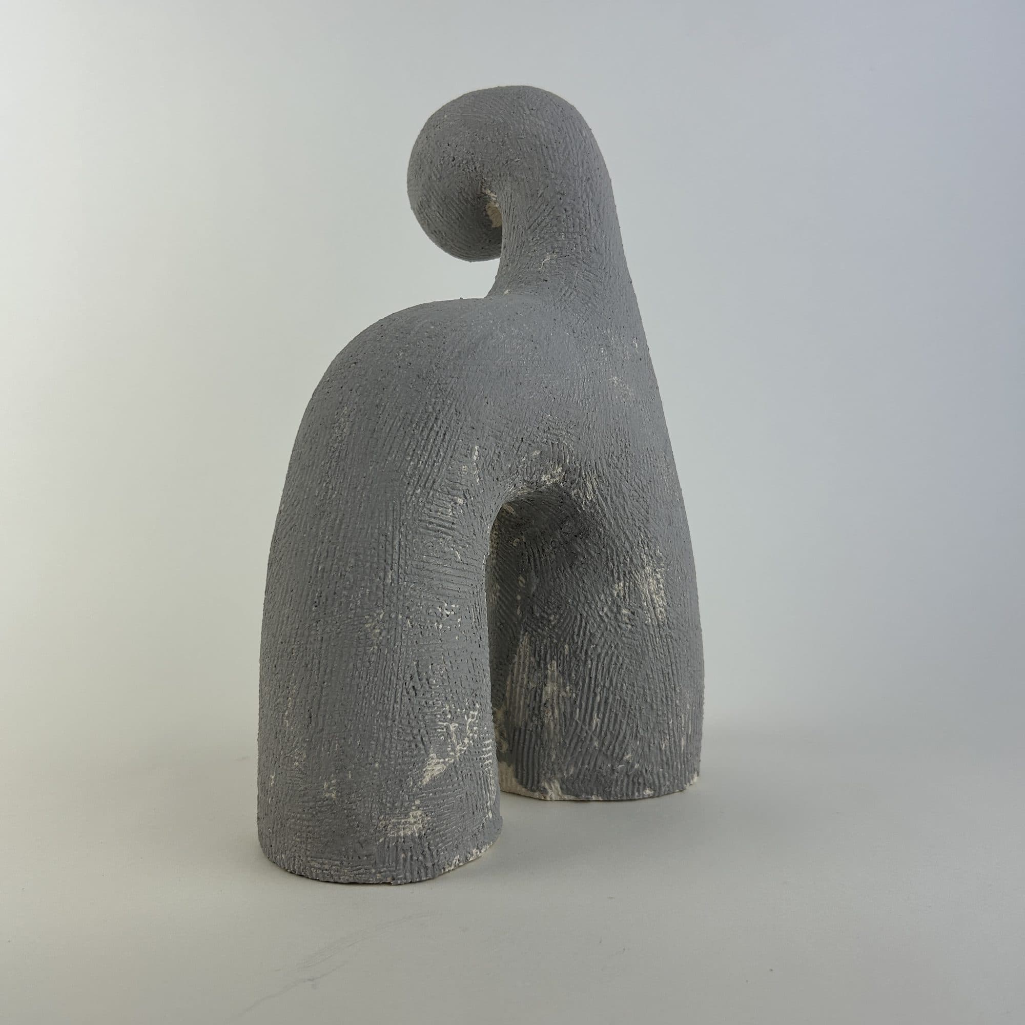 Small grey ceramic arch with a rounded knob at the crest.