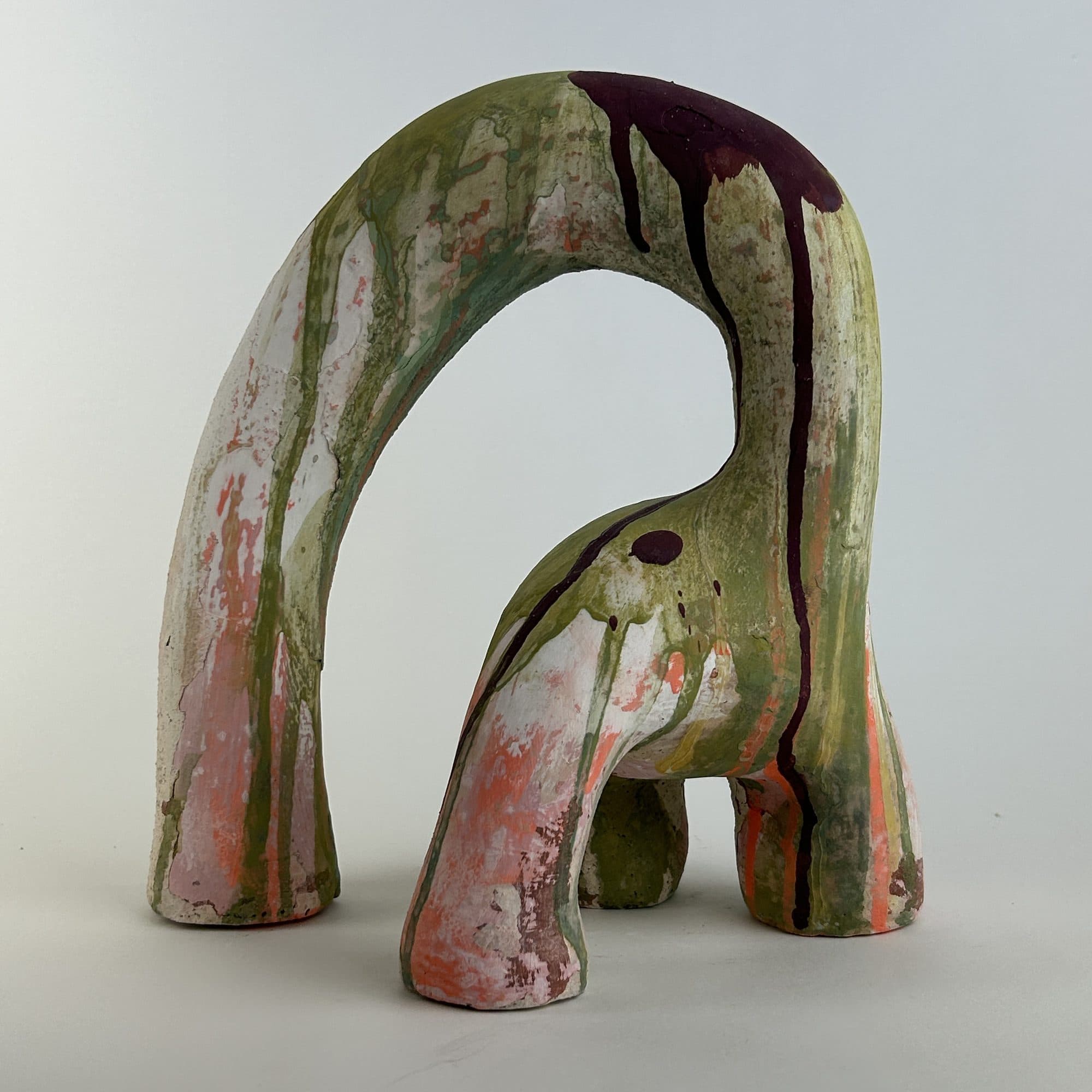 Tall ceramic arch under a glossy olive and pink glaze that pools in the hollows.