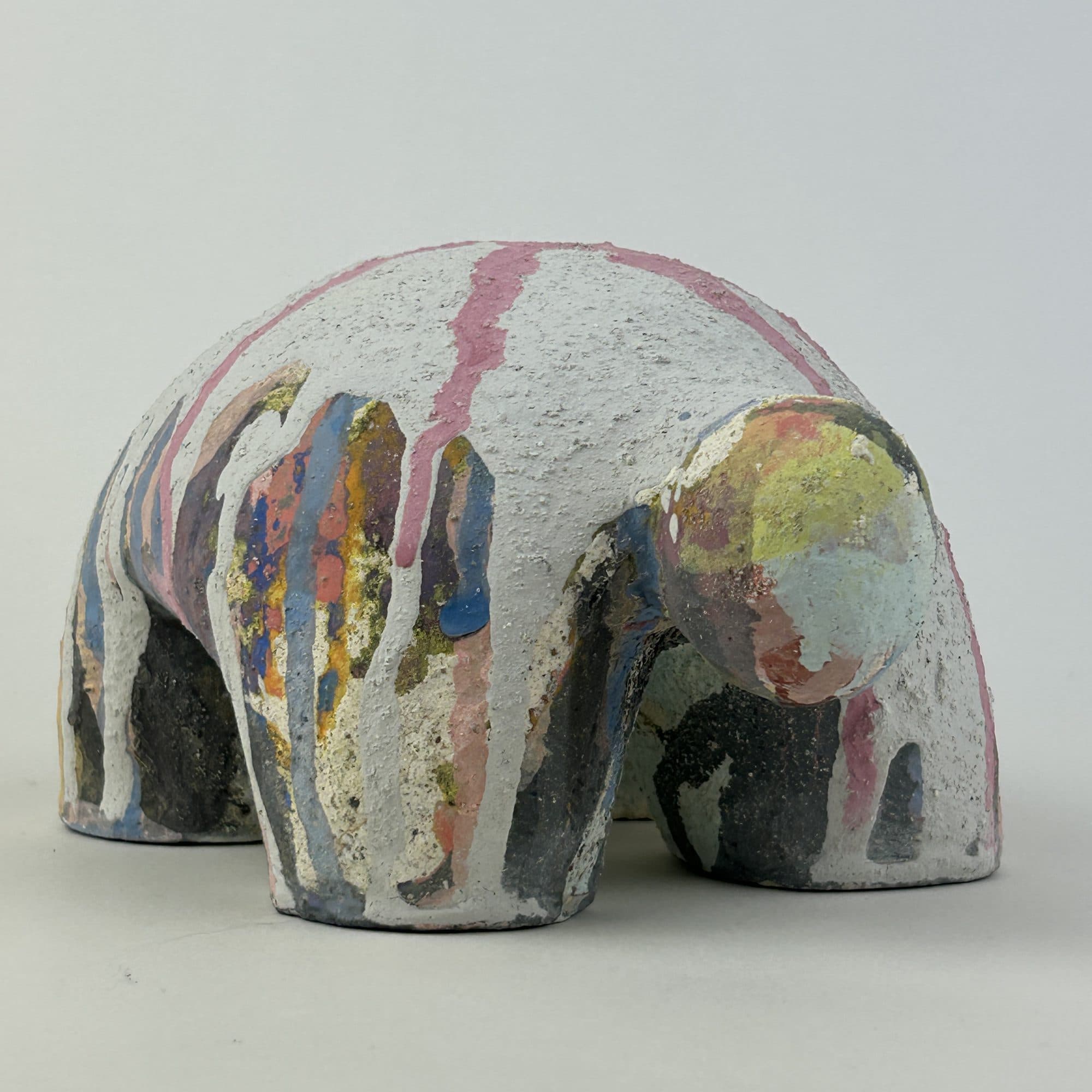 Dome-shaped ceramic sculpture in chalk white with pink, blue and ochre glaze running down the sides.