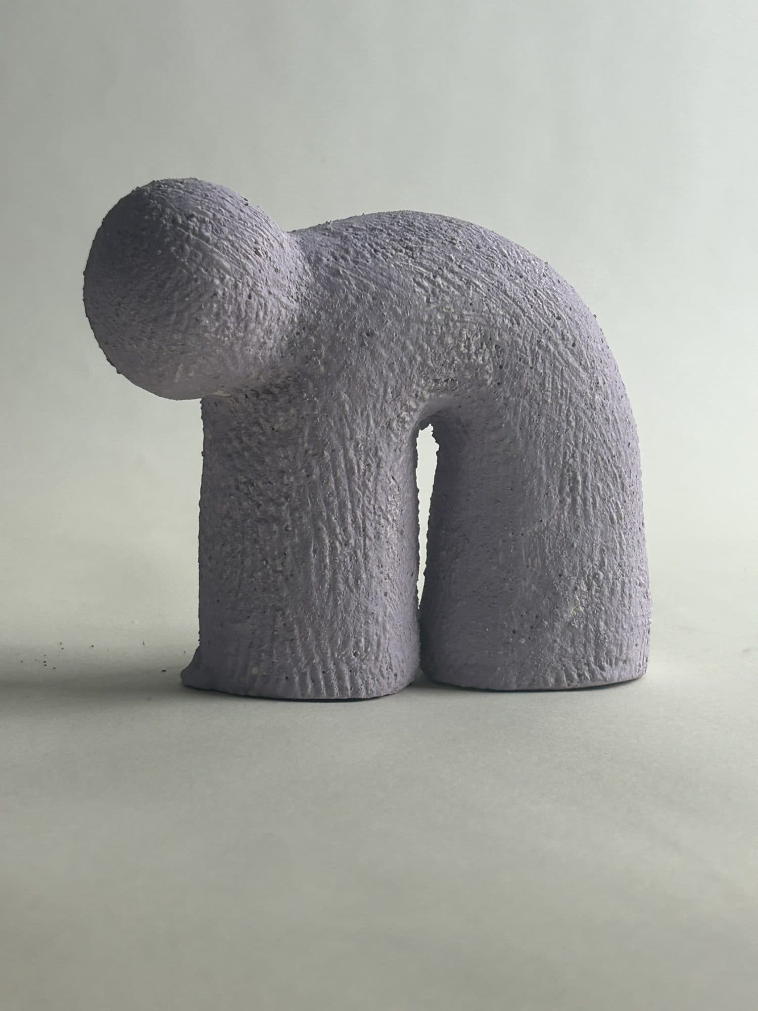 Small ceramic arch in grey-lavender, a rounded knob at the crest above two short legs.