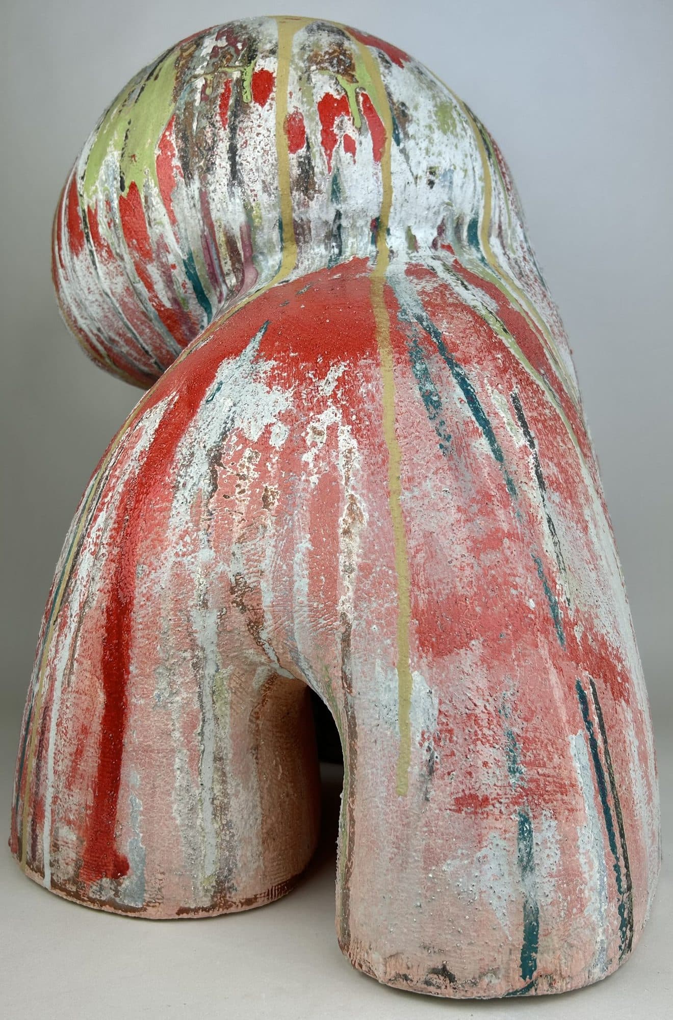 Broad ceramic arch under red and white drip glaze, with flecks of teal caught in the runs.