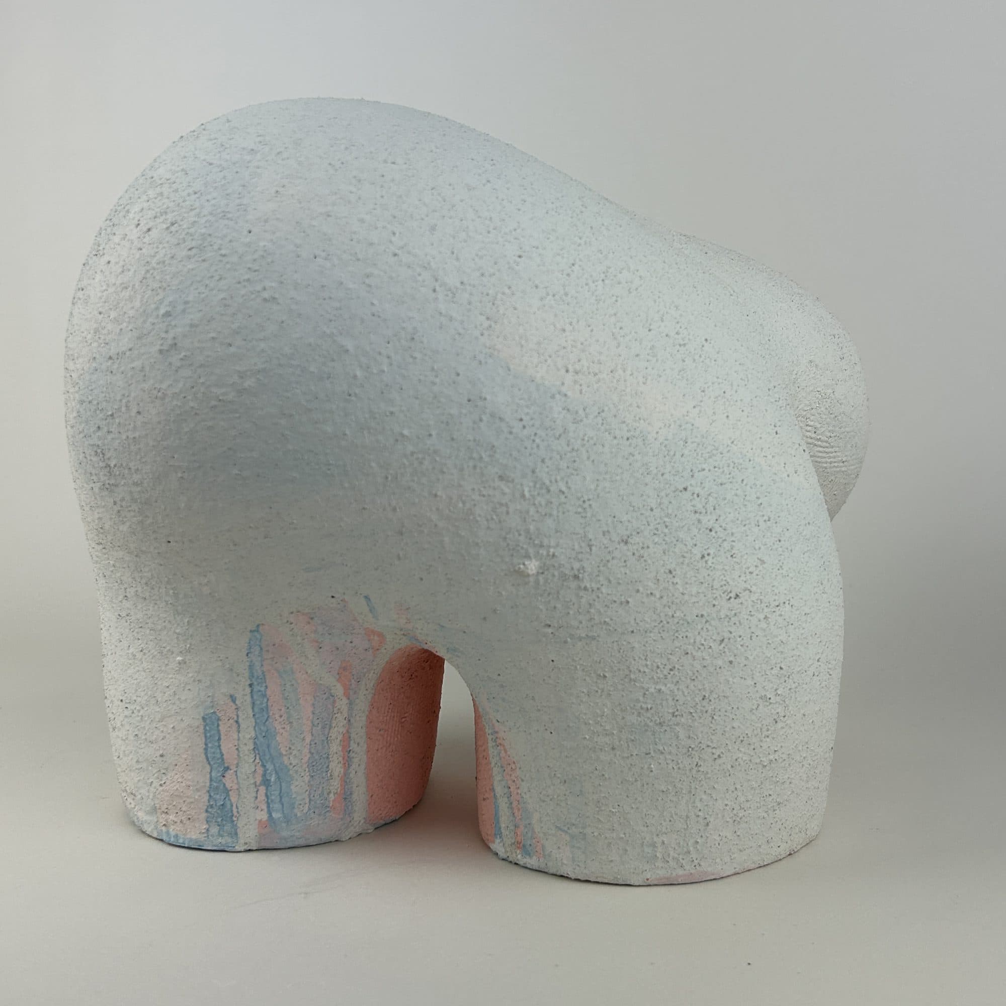 Large chalk-white ceramic sculpture, its low back sweeping down in one long curve to the ground.