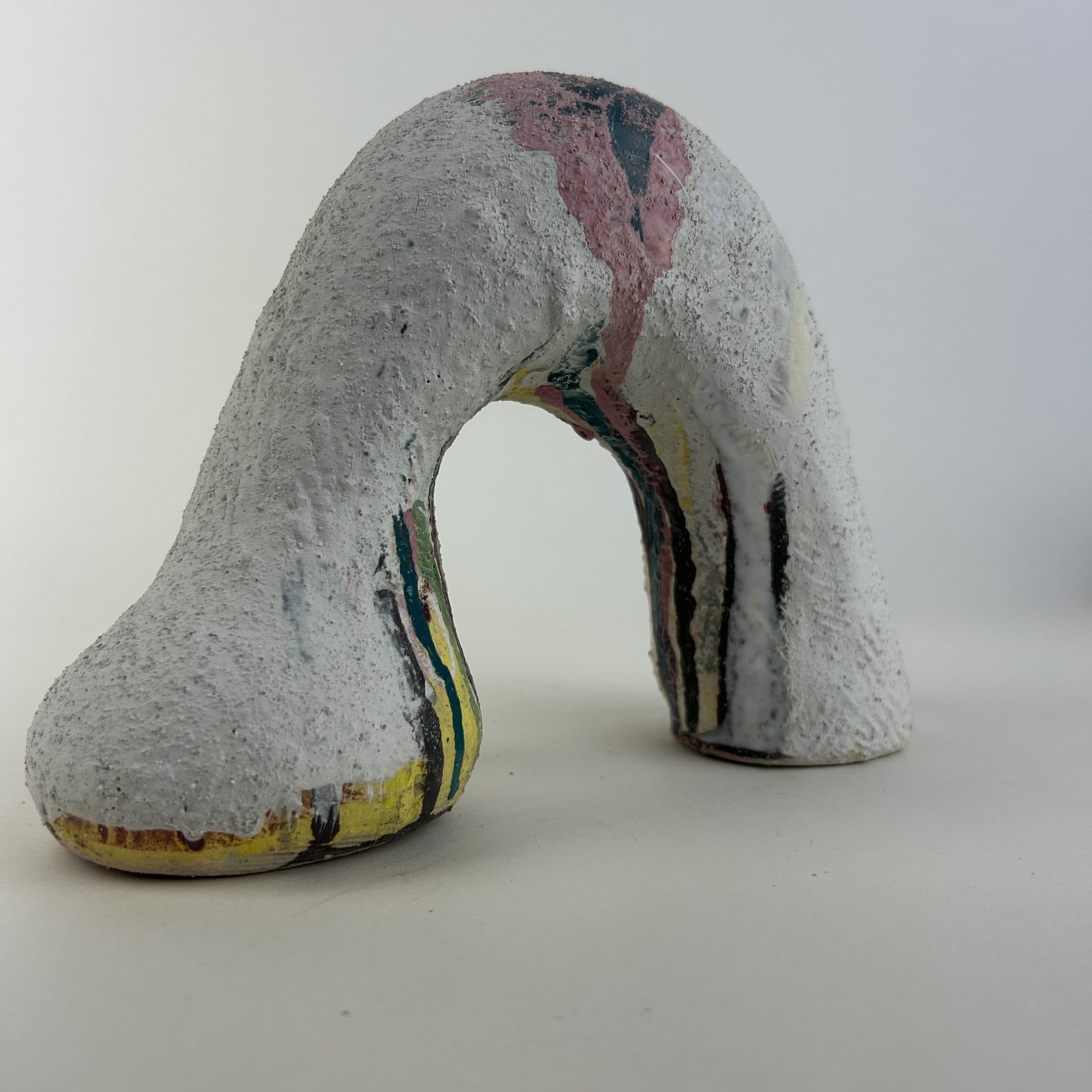 Grey ceramic arch streaked with pink and coral down the length of the form.