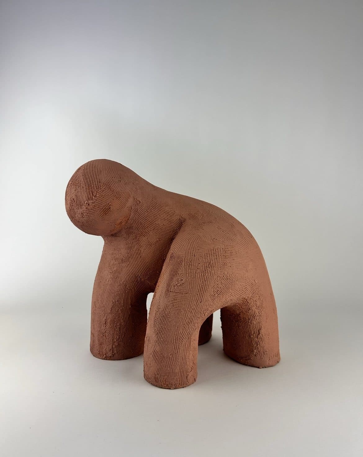 Small unglazed terracotta ceramic sculpture, the raw red clay left bare.