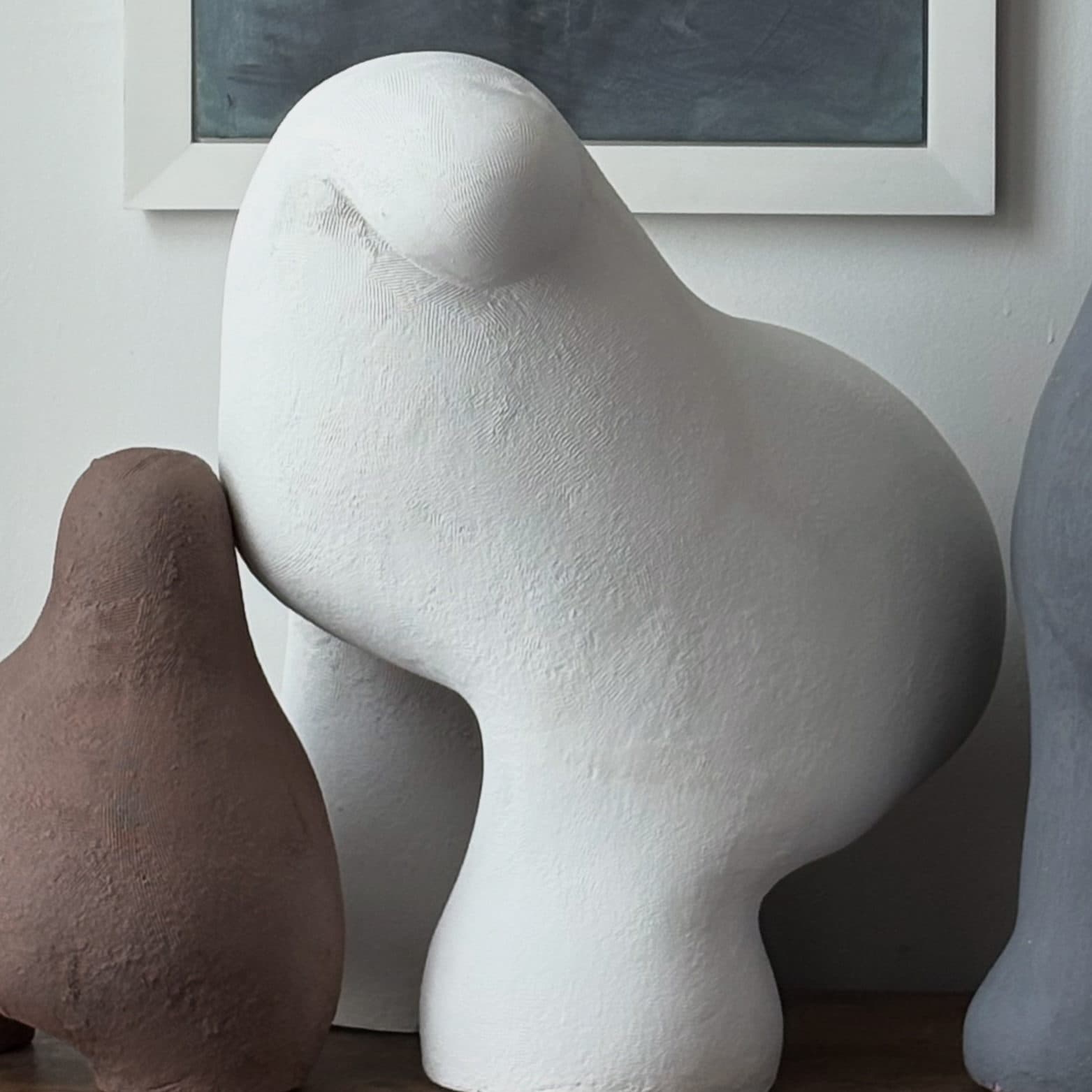 Large white ceramic sculpture with a smooth rounded back and a bulb at the shoulder.